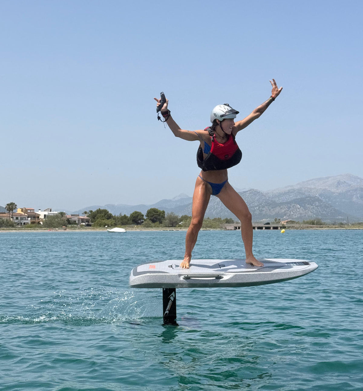 Frau schwebt auf dem eFoil über das ruhige Meer bei Alcúdia