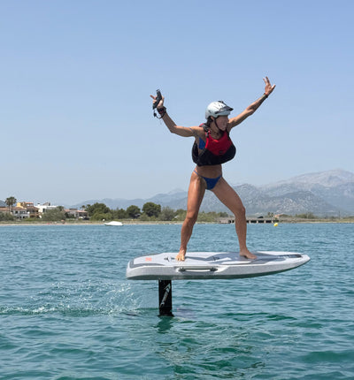 Frau schwebt auf dem eFoil über das ruhige Meer bei Alcúdia